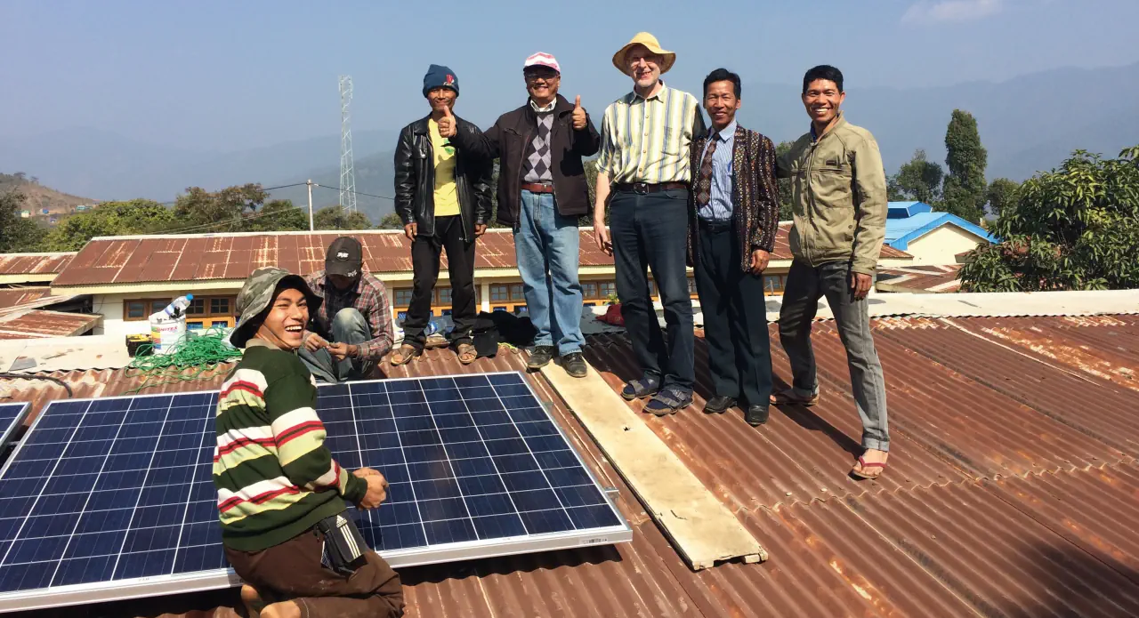 7 Personen bei der Installation der Solarstromanlage in Matupi im Jahr 2016 auf einem Blechdach. Im Hintergund sind weitere Häuser zu sehen