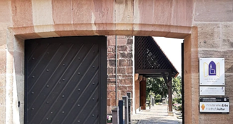 Zu sehen ist das Eingangsportal und die Kirche St.Jobst mit dem Durchgang zum Friedhof